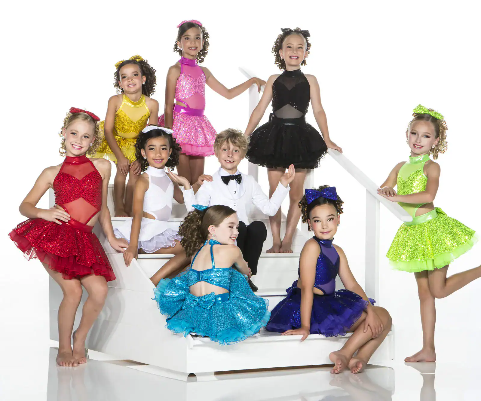 Children in colorful dance costumes posing on white stairs