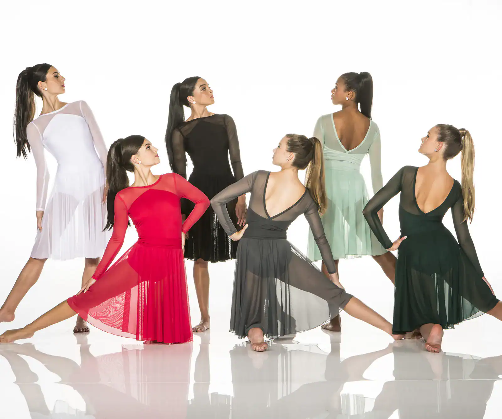 Six women pose in colorful sheer dance dresses.