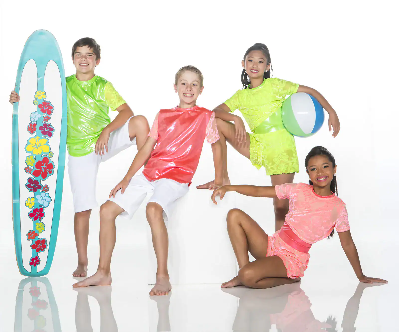 Four children pose with surfboard and beach ball.