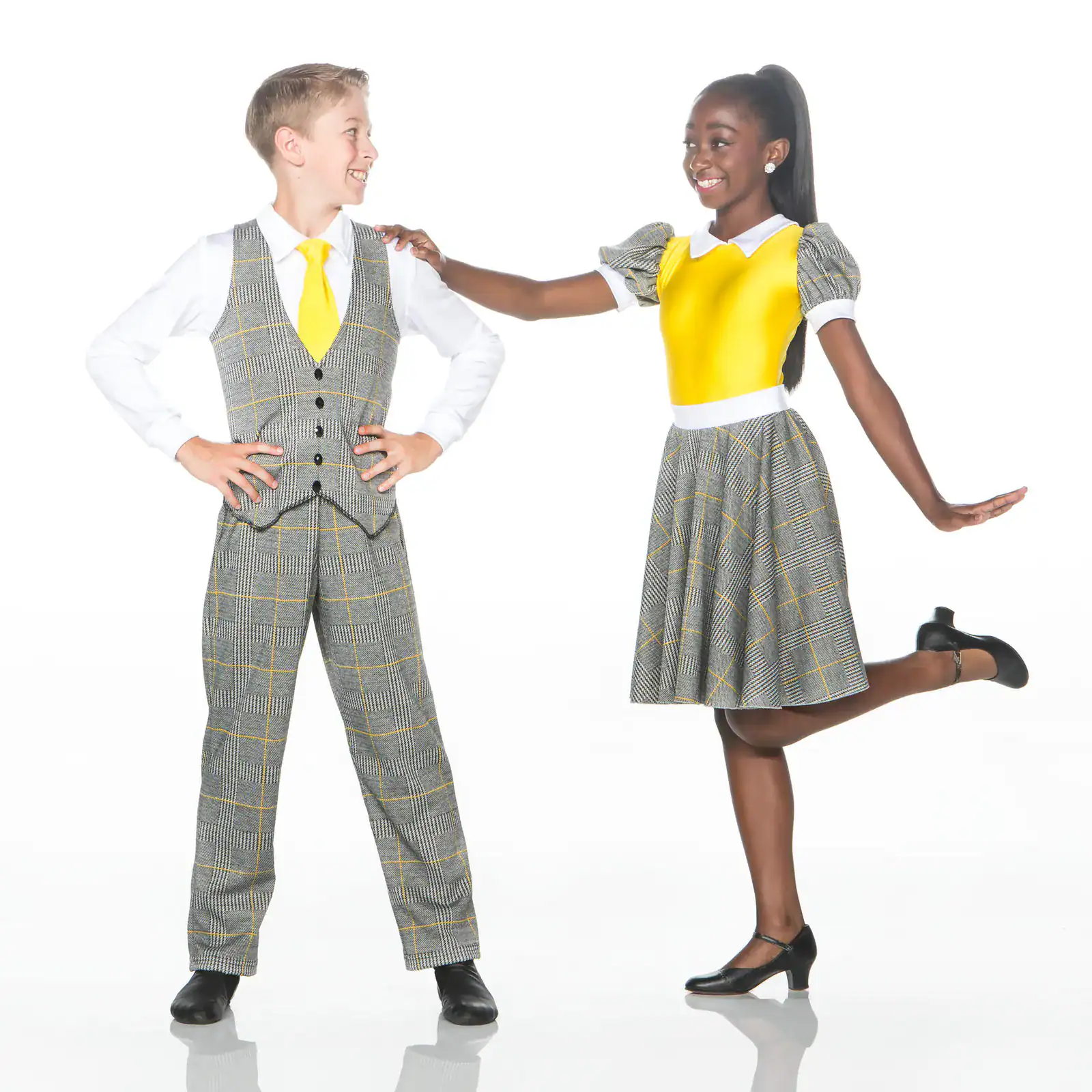 Two children smiling in coordinated yellow and plaid outfits