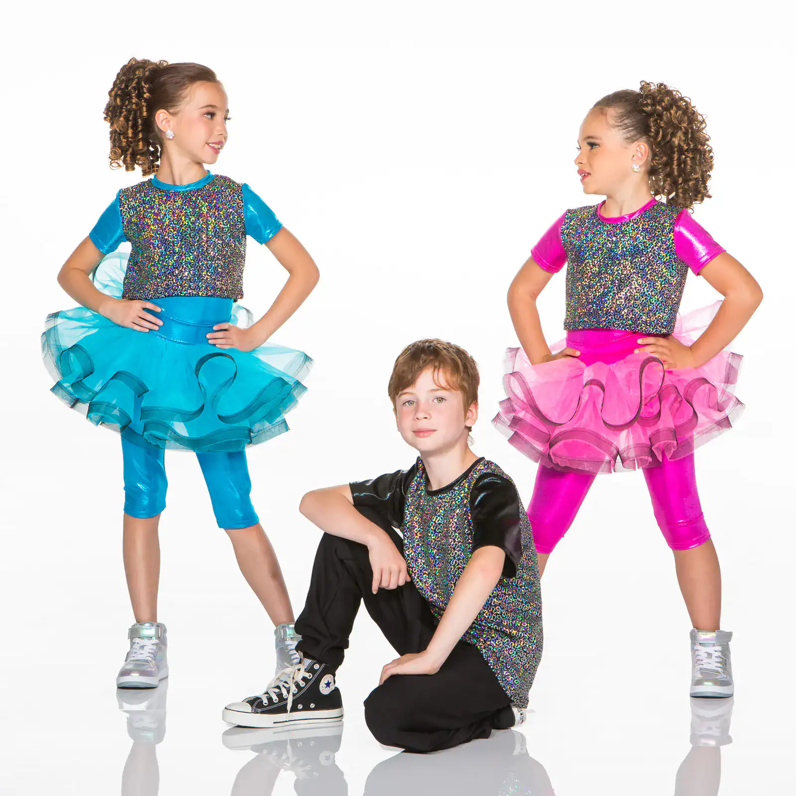 Three young dancers wearing colorful glittery performance costumes