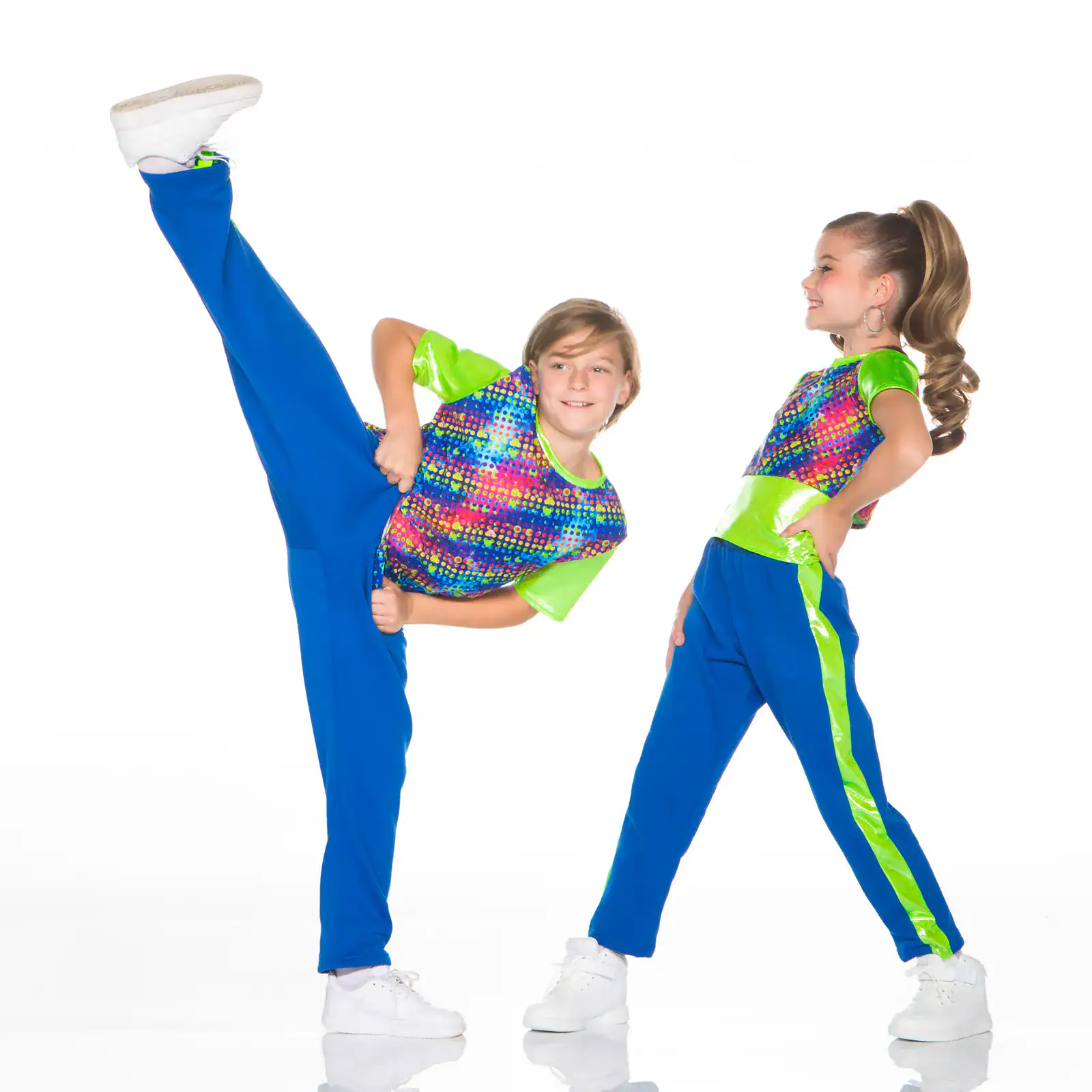 Two young dancers in colorful costumes, one performing high kick